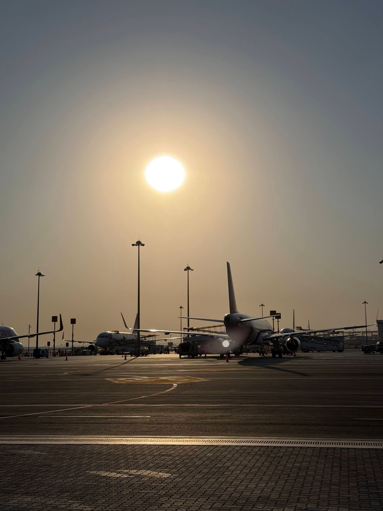 Sunrise through the haze over parked Air Arabia planes at Sharjah airport