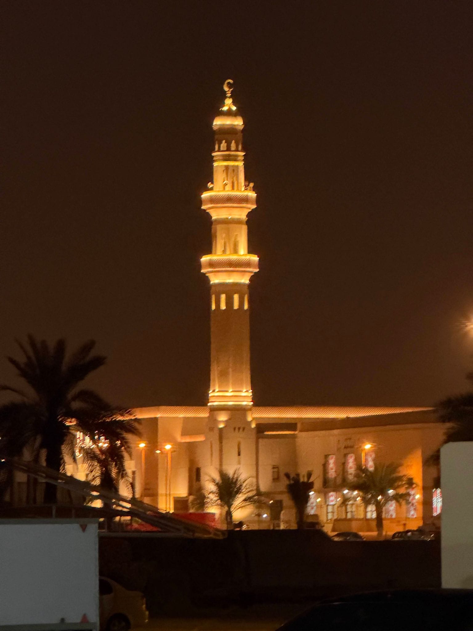 A lit minaret before dawn next to the Sharjah airport hotel